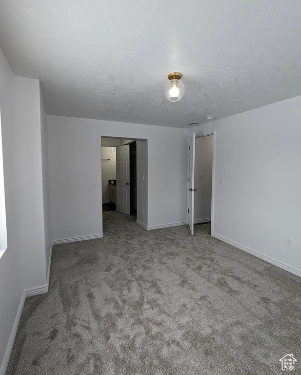Carpeted empty room featuring baseboards and a textured ceiling
