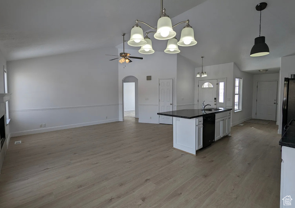 Kitchen featuring a sink, ceiling fan with notable chandelier, black appliances, arched walkways, and dark countertops