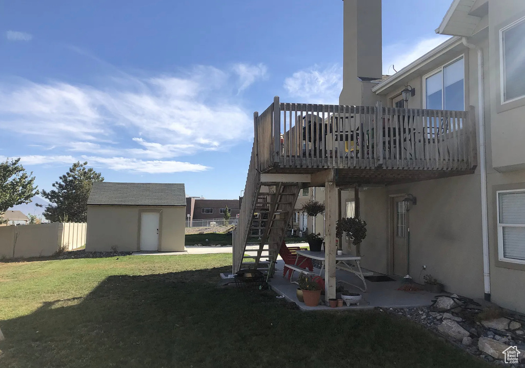 View of yard featuring fence, an outdoor structure, stairs, a wooden deck, and a storage shed