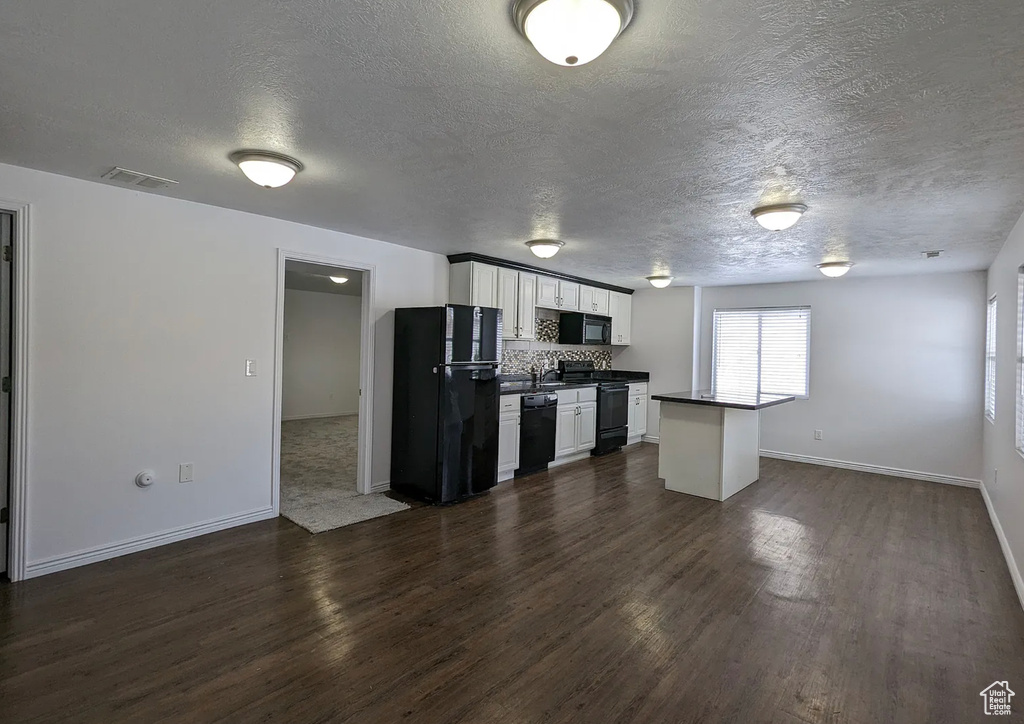Kitchen featuring dark countertops, a textured ceiling, black appliances, and visible vents