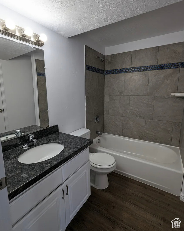 Full bathroom featuring toilet, wood finished floors, bathing tub / shower combination, a textured ceiling, and vanity