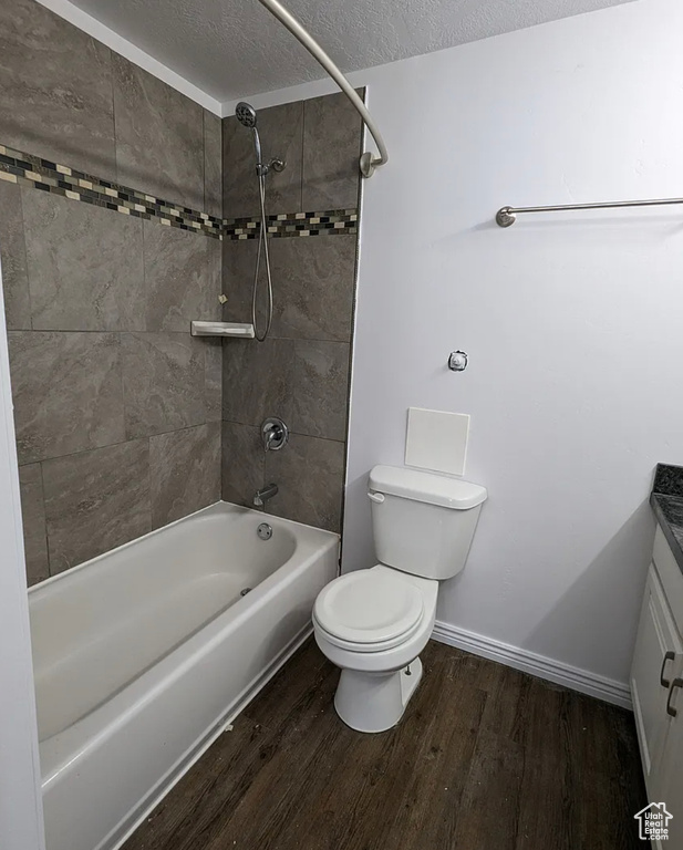 Full bathroom with toilet, wood finished floors, vanity, a textured ceiling, and tub / shower combination