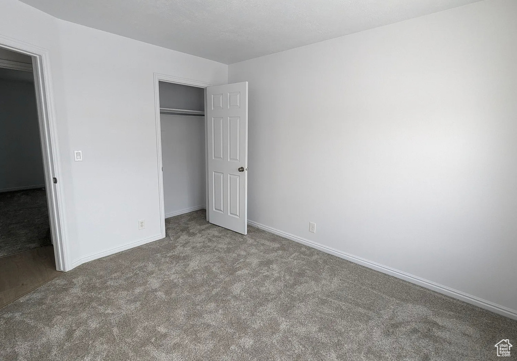 Unfurnished bedroom with carpet, a closet, and baseboards