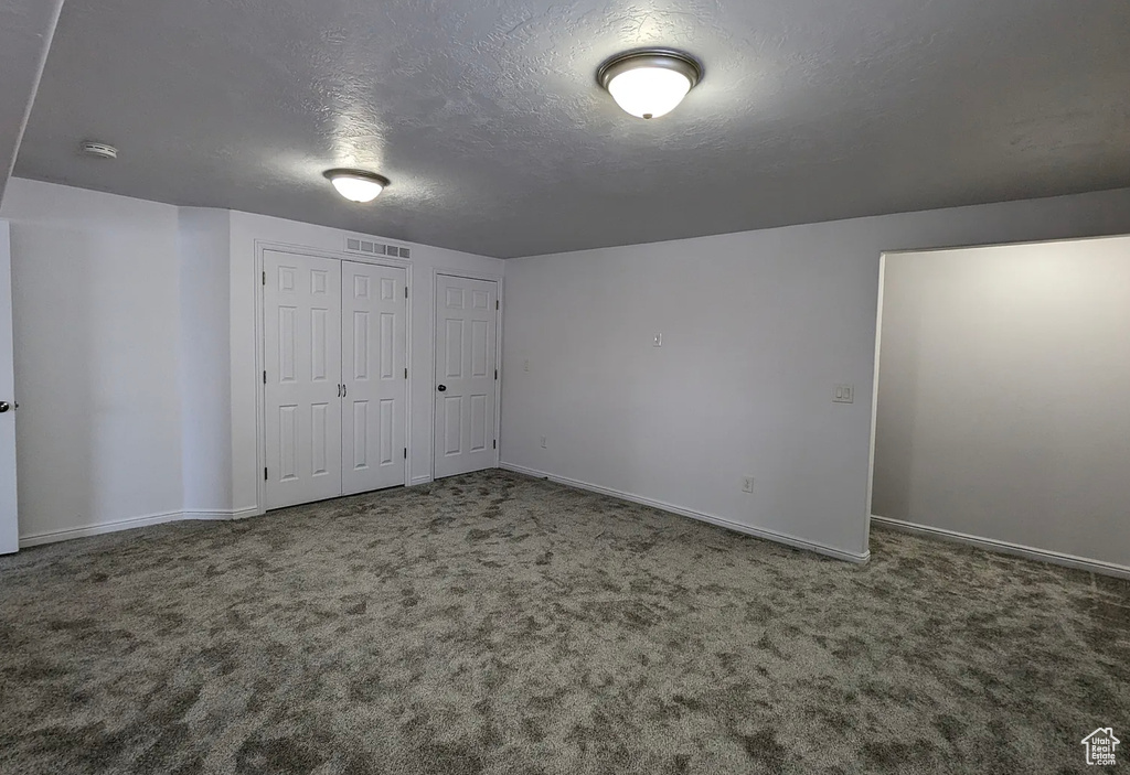 Unfurnished bedroom featuring carpet flooring, a textured ceiling, visible vents, and baseboards