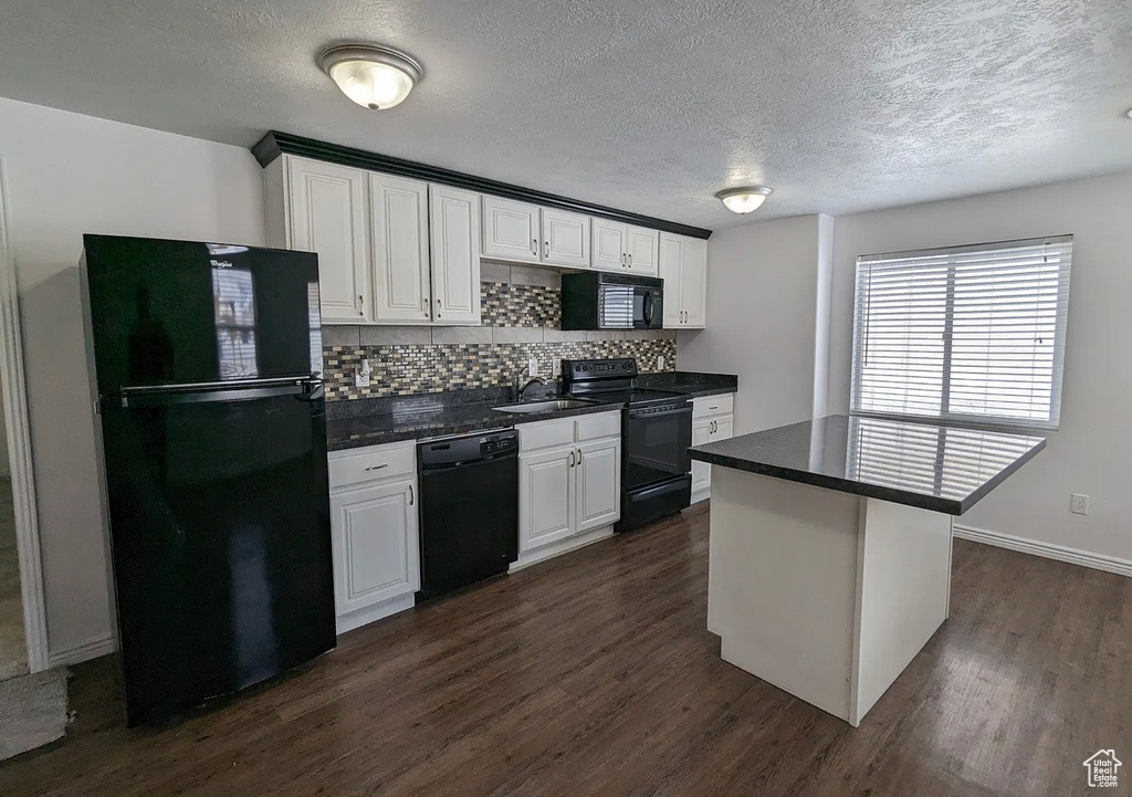 Kitchen with a sink, white cabinets, dark wood finished floors, black appliances, and decorative backsplash