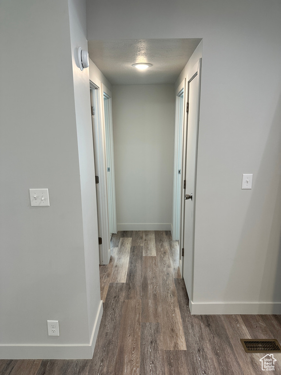 Hallway featuring baseboards, visible vents, and wood finished floors