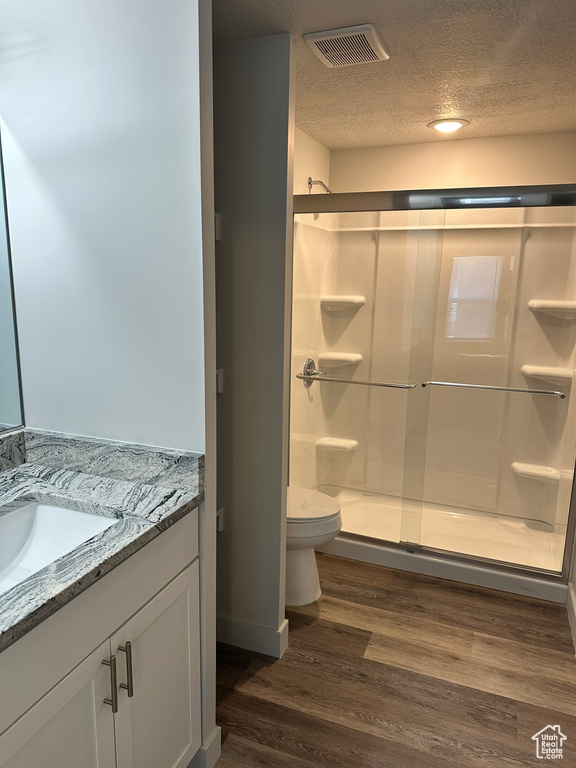 Bathroom featuring toilet, vanity, visible vents, and a stall shower