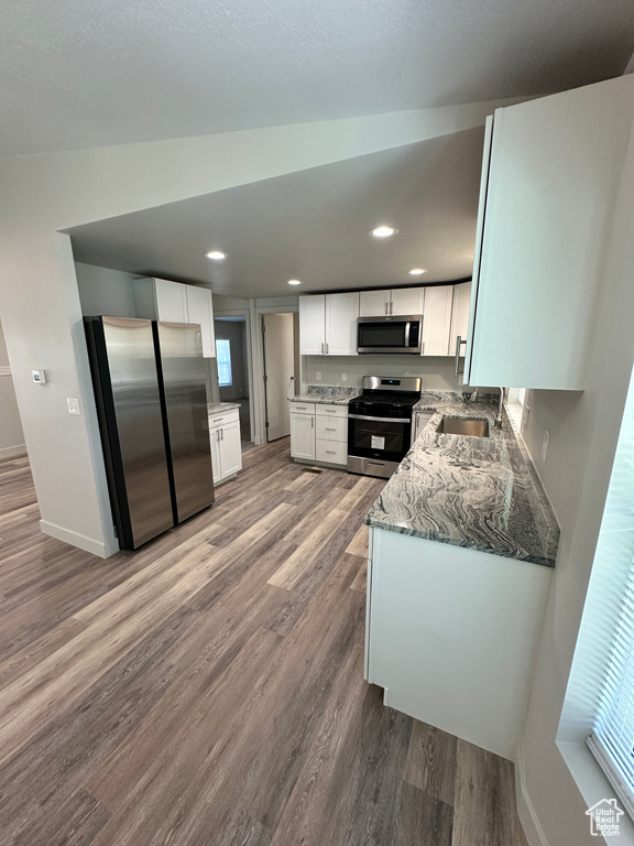 Kitchen featuring a sink, wood finished floors, white cabinets, and appliances with stainless steel finishes