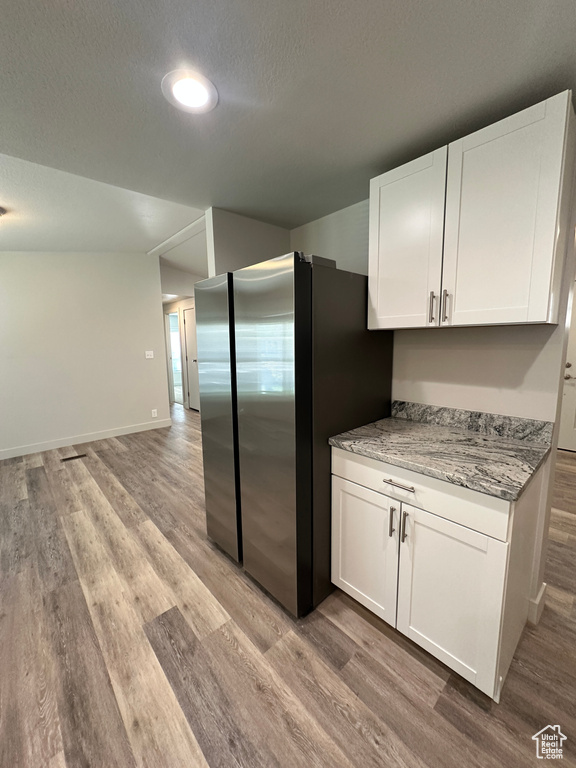 Kitchen featuring freestanding refrigerator, white cabinetry, and light wood-style flooring