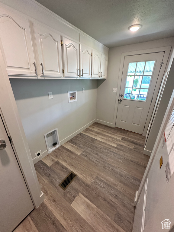 Clothes washing area featuring hookup for a washing machine, visible vents, wood finished floors, hookup for an electric dryer, and cabinet space