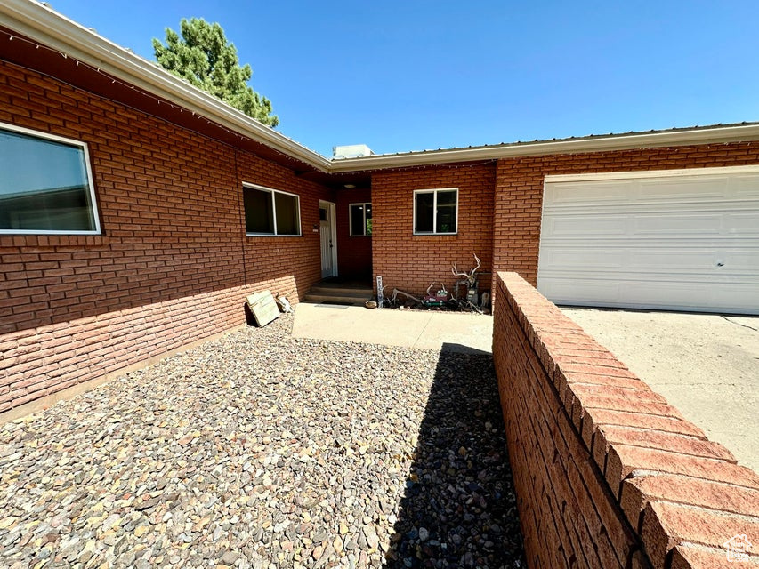 Property entrance featuring a garage and brick siding