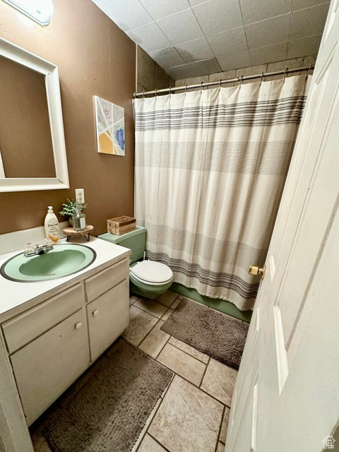 Full bathroom with curtained shower, vanity, and toilet