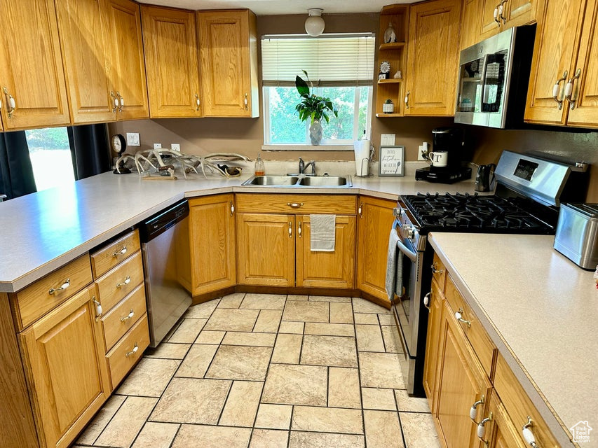 Kitchen featuring a wealth of natural light, appliances with stainless steel finishes, stone tile floors, and a sink