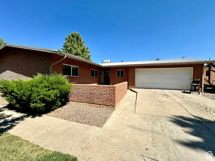Single story home featuring concrete driveway, a garage, and brick siding