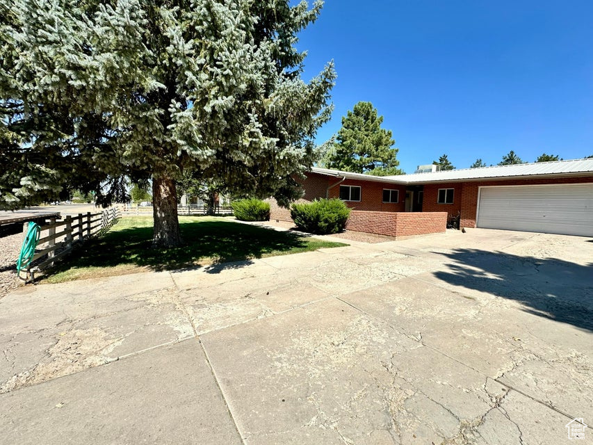 View of front facade with fence, a garage, brick siding, and driveway