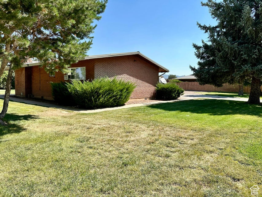 View of property exterior with brick siding and a lawn