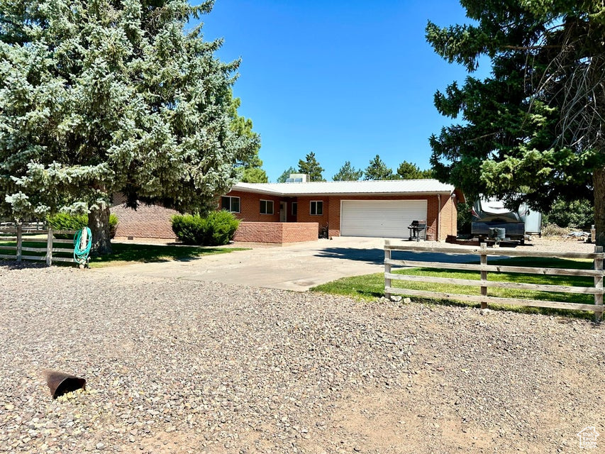 Single story home featuring fence, an attached garage, brick siding, and driveway