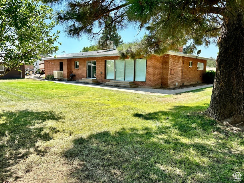 Rear view of house featuring a yard, brick siding, and entry steps