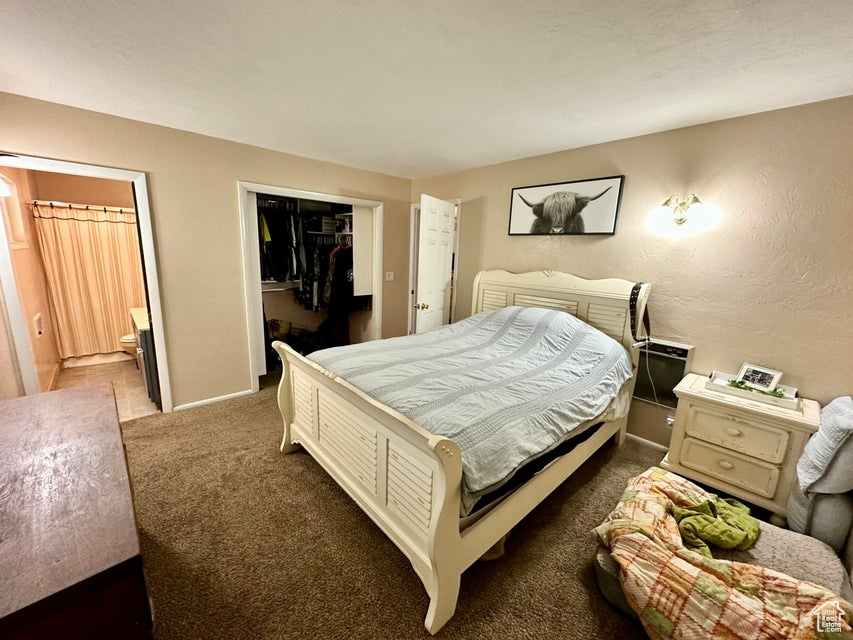 Carpeted bedroom featuring baseboards, ensuite bathroom, a closet, and a spacious closet