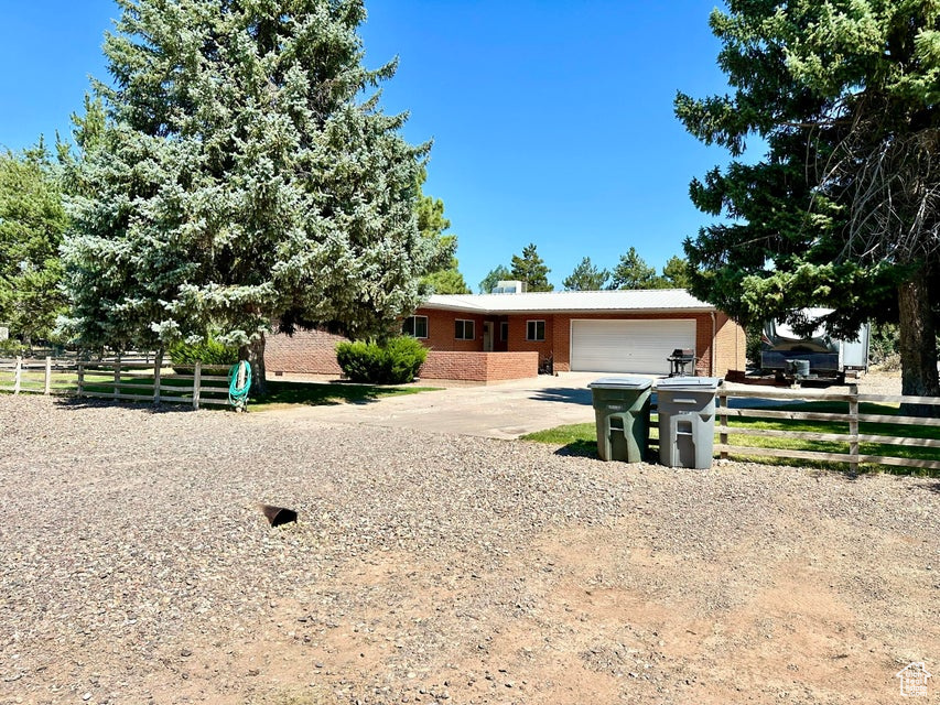 Ranch-style house featuring concrete driveway, brick siding, fence, and a garage