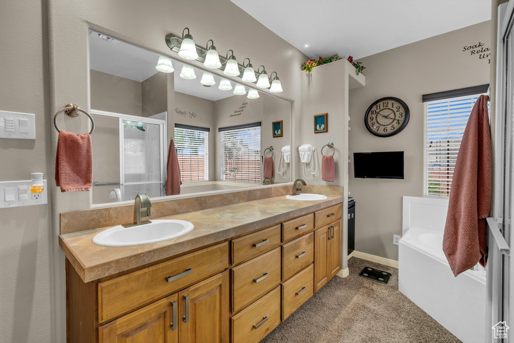 Bathroom featuring a sink, a bath, and plenty of natural light