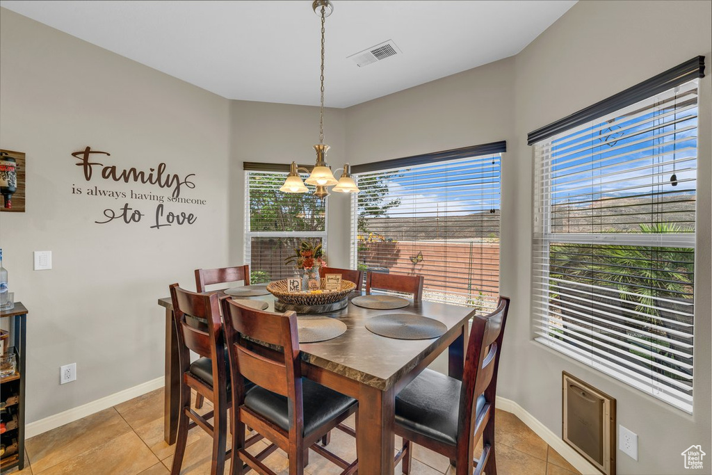 Dining room with light tile patterned floors, baseboards, a chandelier, and visible vents