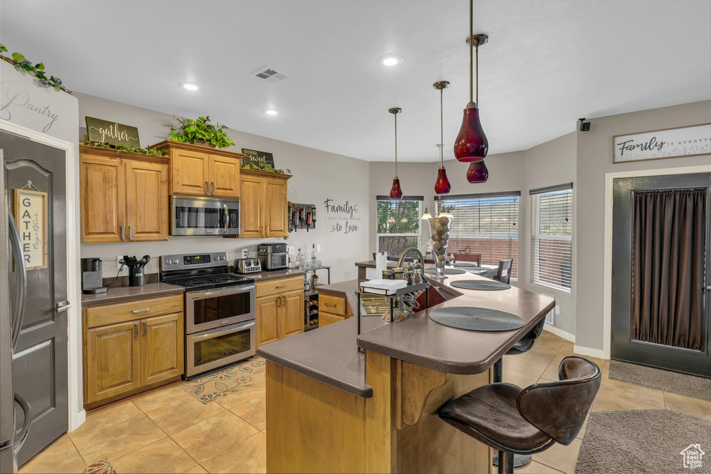 Kitchen with light tile patterned floors, dark countertops, and stainless steel appliances