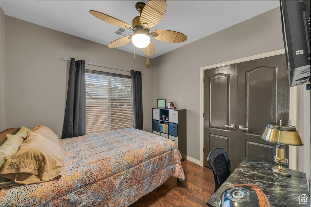 Bedroom with a closet, baseboards, ceiling fan, visible vents, and dark wood-style floors