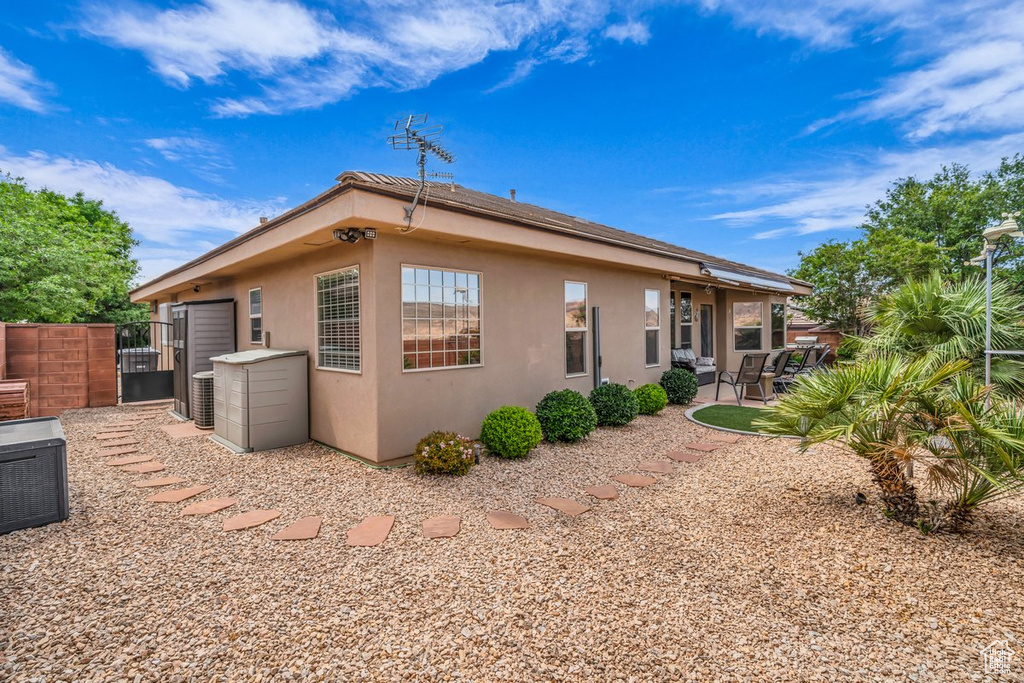 View of property exterior with a patio, central AC unit, stucco siding, and a gate