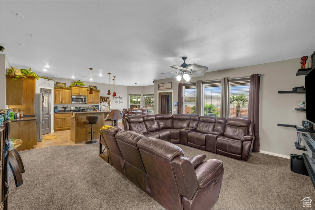 Living room with light colored carpet, ceiling fan, and plenty of natural light