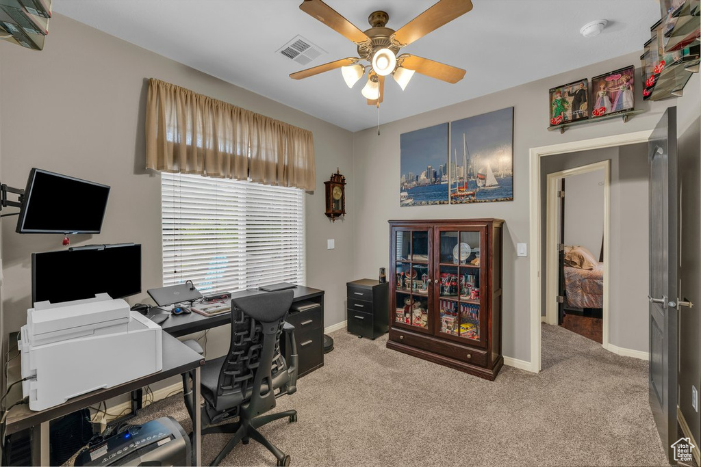 Carpeted office space featuring baseboards, a ceiling fan, and visible vents