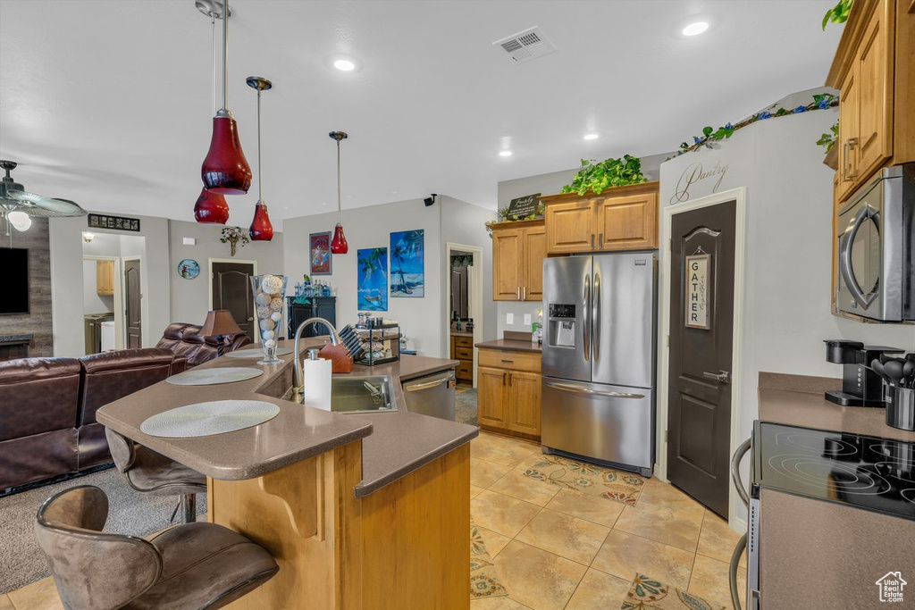 Kitchen with a sink, dark countertops, open floor plan, visible vents, and appliances with stainless steel finishes