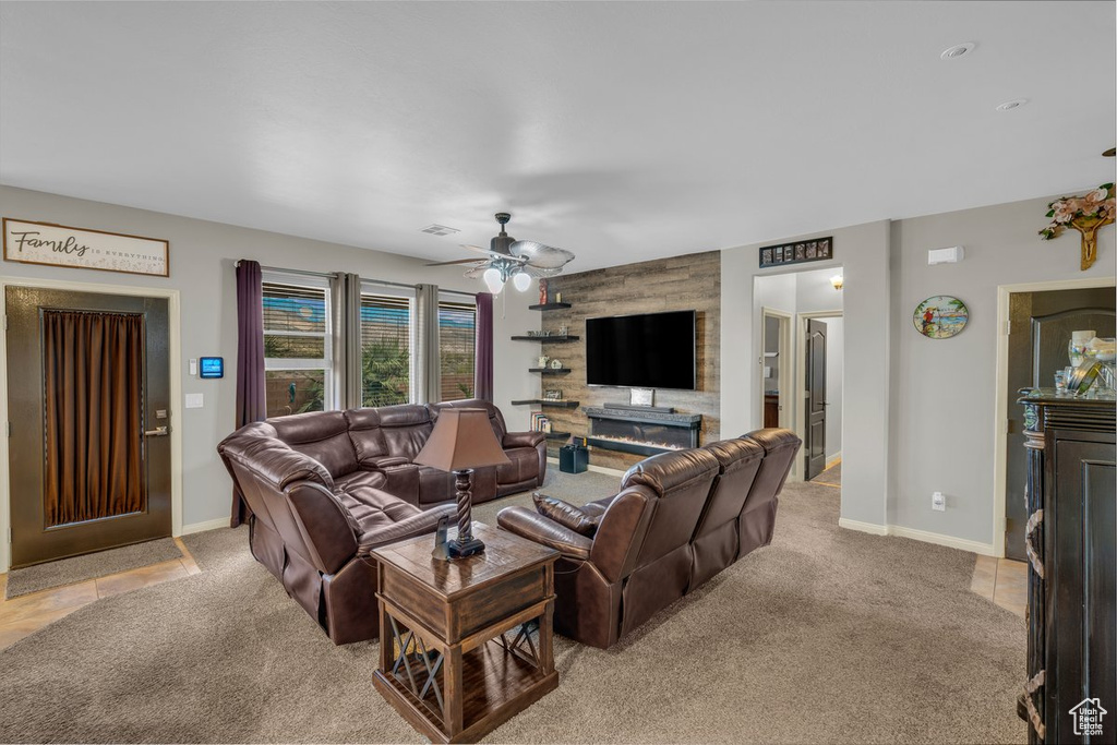 Living area with a large fireplace, baseboards, a ceiling fan, and light colored carpet