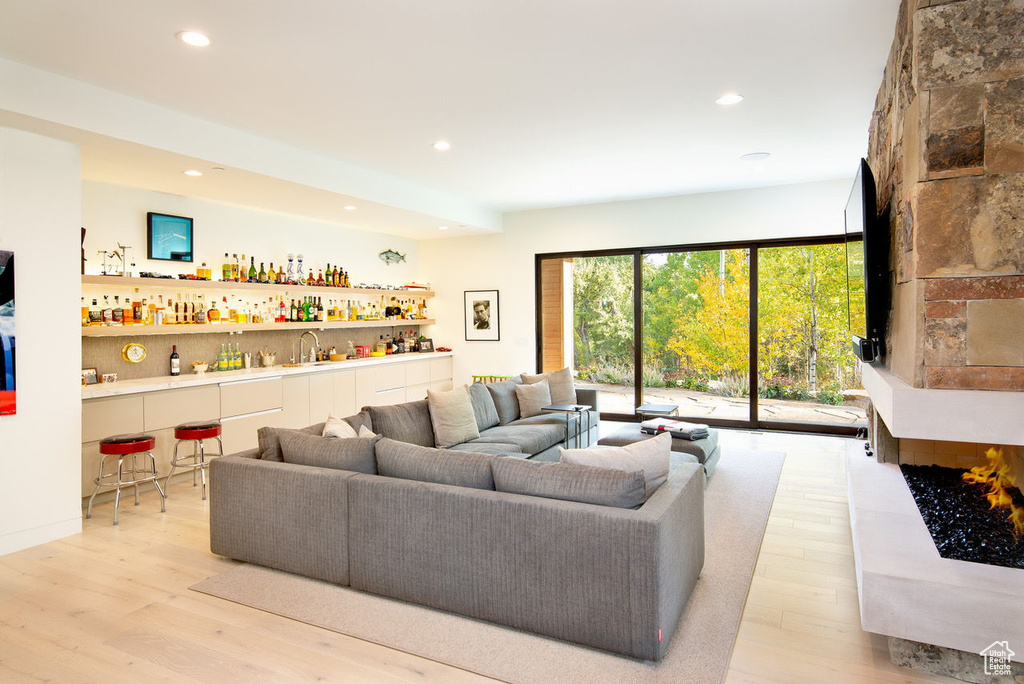 Living area with recessed lighting, light wood-style floors, and bar area
