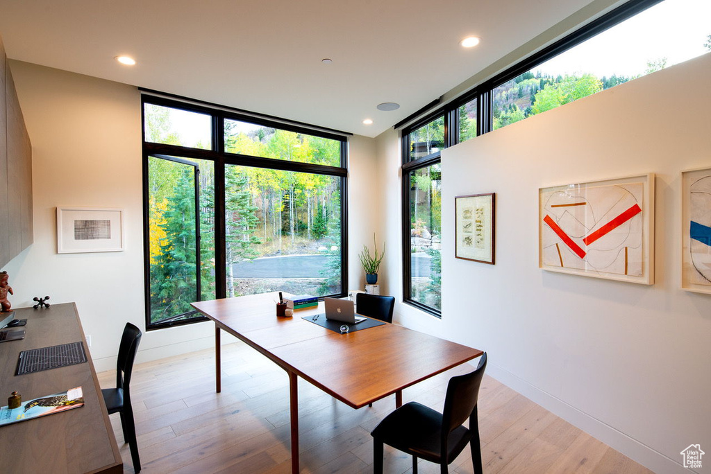 Dining space featuring baseboards, a wall of windows, recessed lighting, and light wood-type flooring