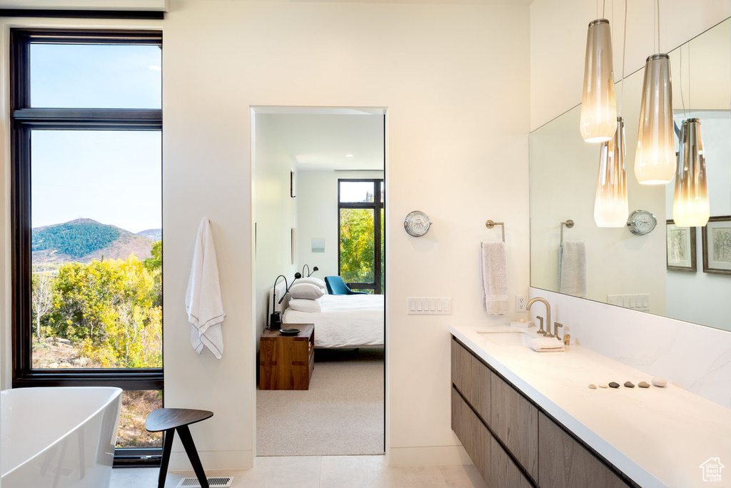 Ensuite bathroom featuring a mountain view, tile patterned flooring, connected bathroom, vanity, and a freestanding tub