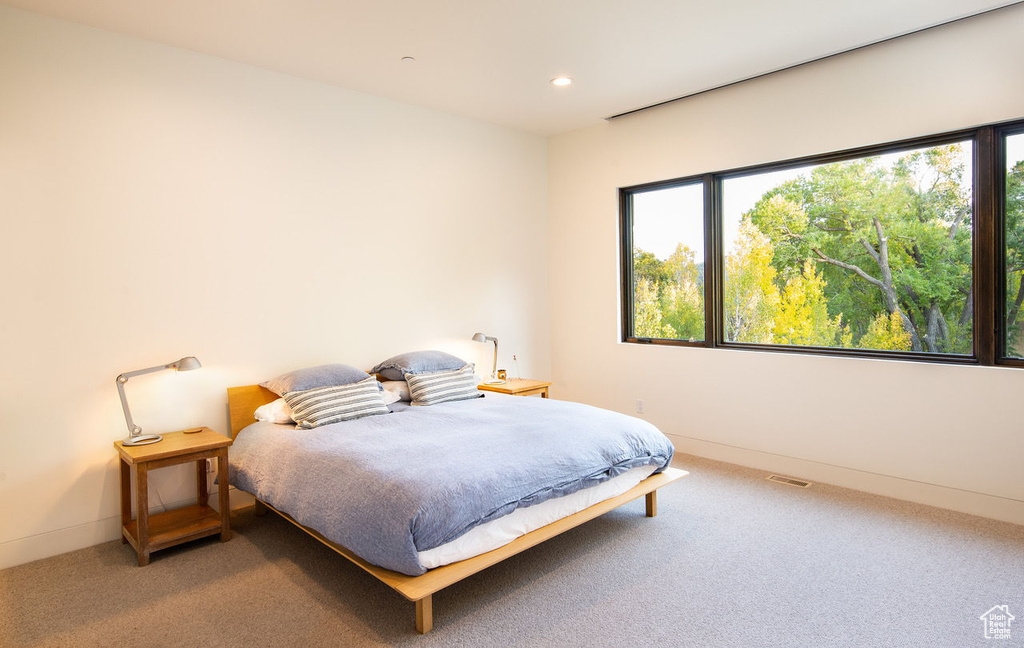 Carpeted bedroom with multiple windows, visible vents, baseboards, and recessed lighting