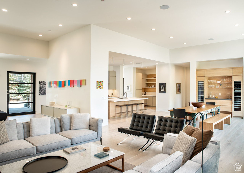 Living room with light wood-style floors, wine cooler, and recessed lighting