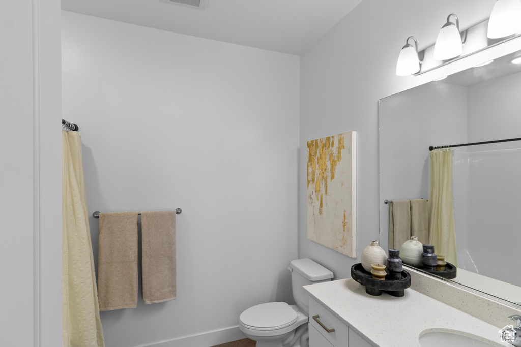 Full bathroom with toilet, a shower with curtain, visible vents, baseboards, and vanity