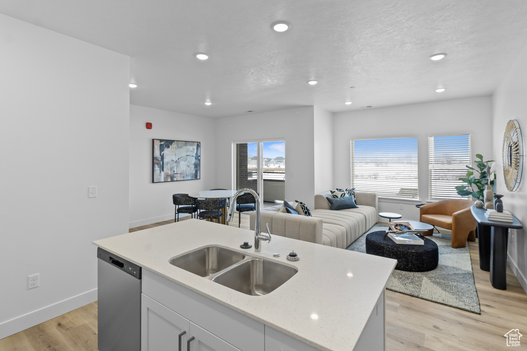 Kitchen featuring recessed lighting, dishwasher, open floor plan, and a sink