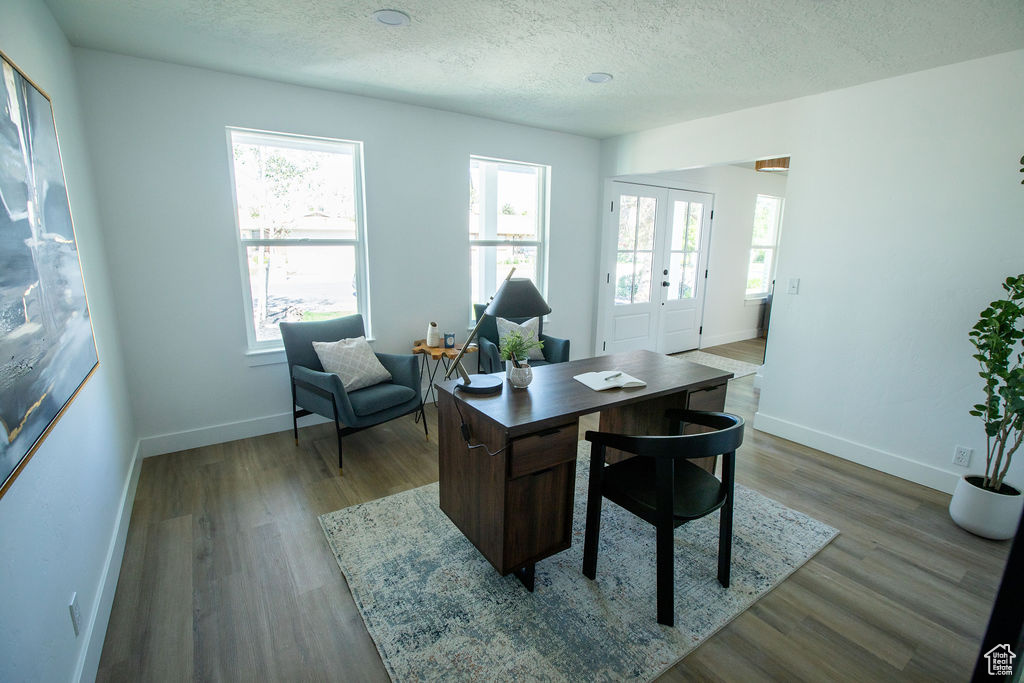 Office space featuring baseboards, wood finished floors, a textured ceiling, and french doors