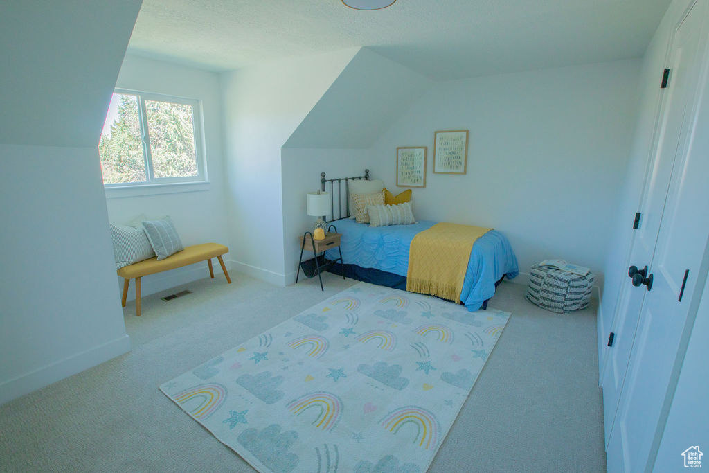 Bedroom with carpet floors, baseboards, and lofted ceiling