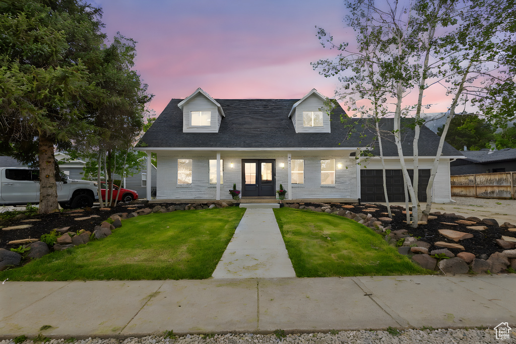 Cape cod-style house featuring french doors, covered porch, a shingled roof, and an attached garage