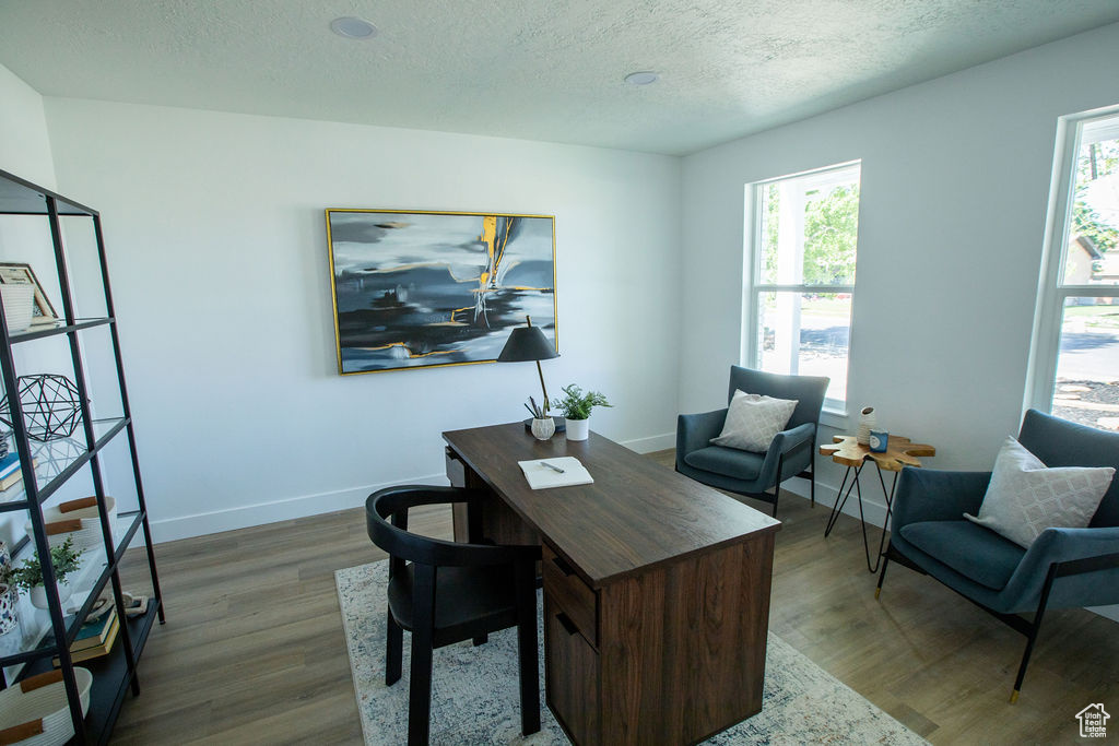 Home office with dark wood-type flooring, baseboards, and a textured ceiling