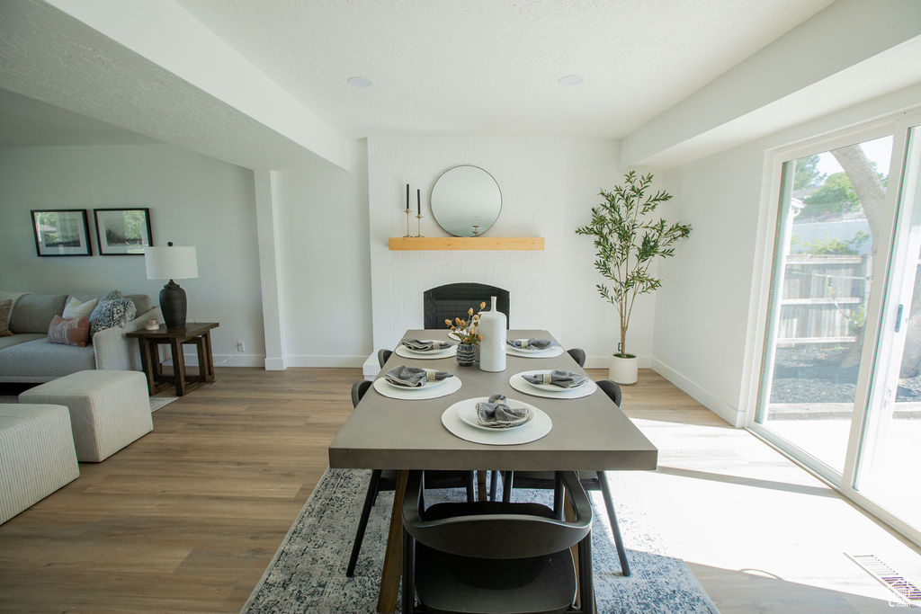 Dining space featuring a brick fireplace, light wood finished floors, and baseboards