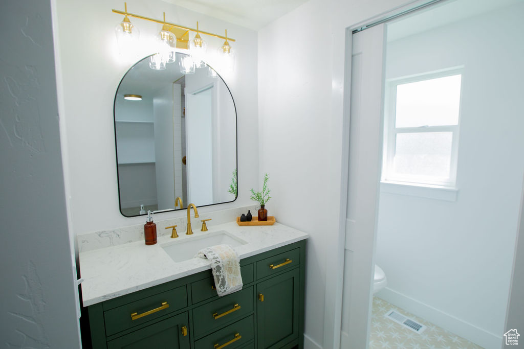 Bathroom featuring vanity, toilet, and baseboards