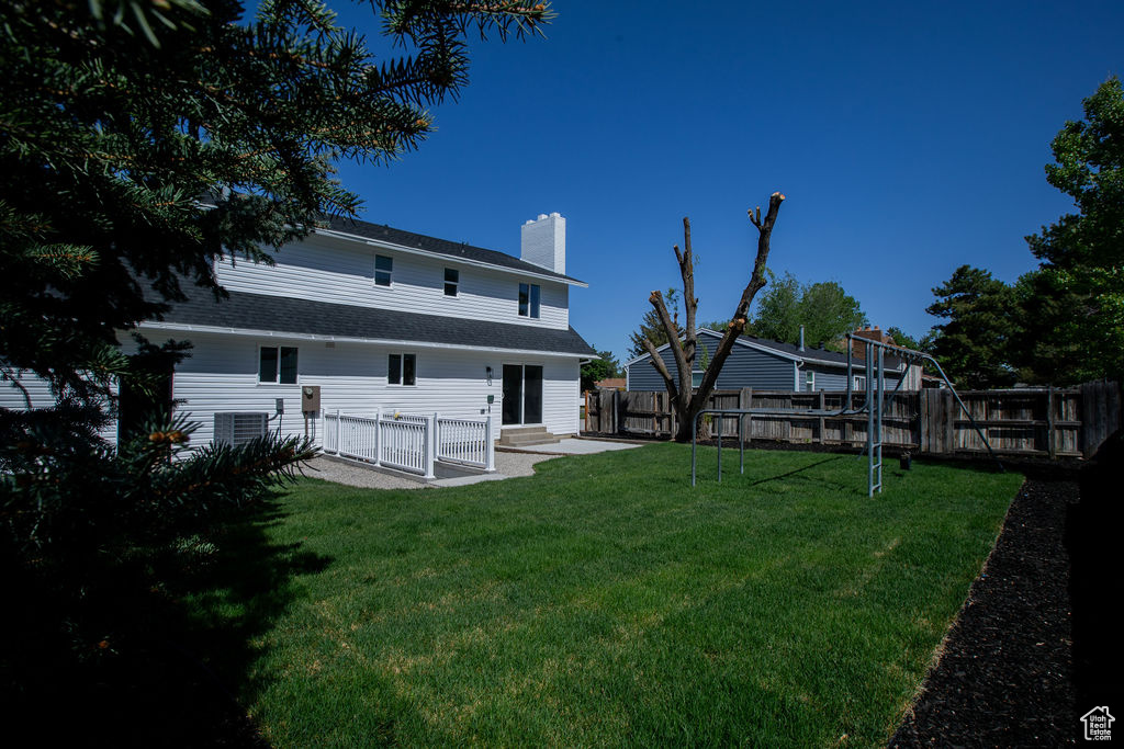 Rear view of property with a chimney, a patio, and central AC