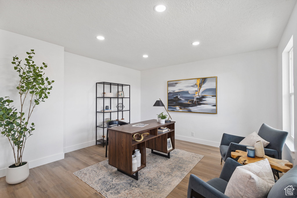 Home office with baseboards, light wood-style floors, recessed lighting, and a textured ceiling