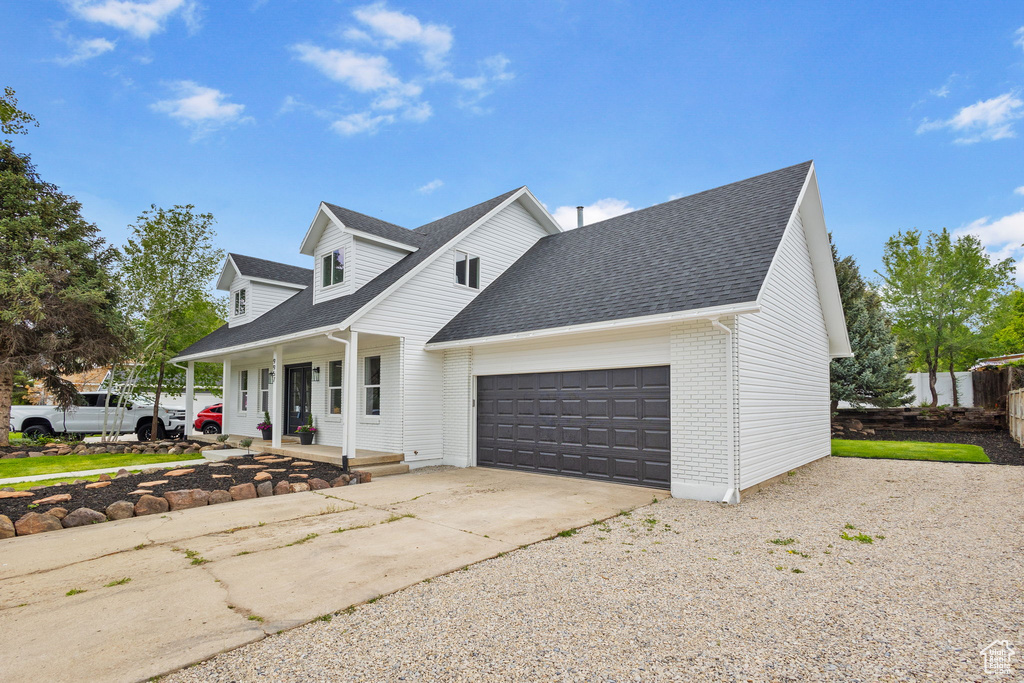 View of front of house featuring covered porch, a garage, concrete driveway, brick siding, and a shingled roof