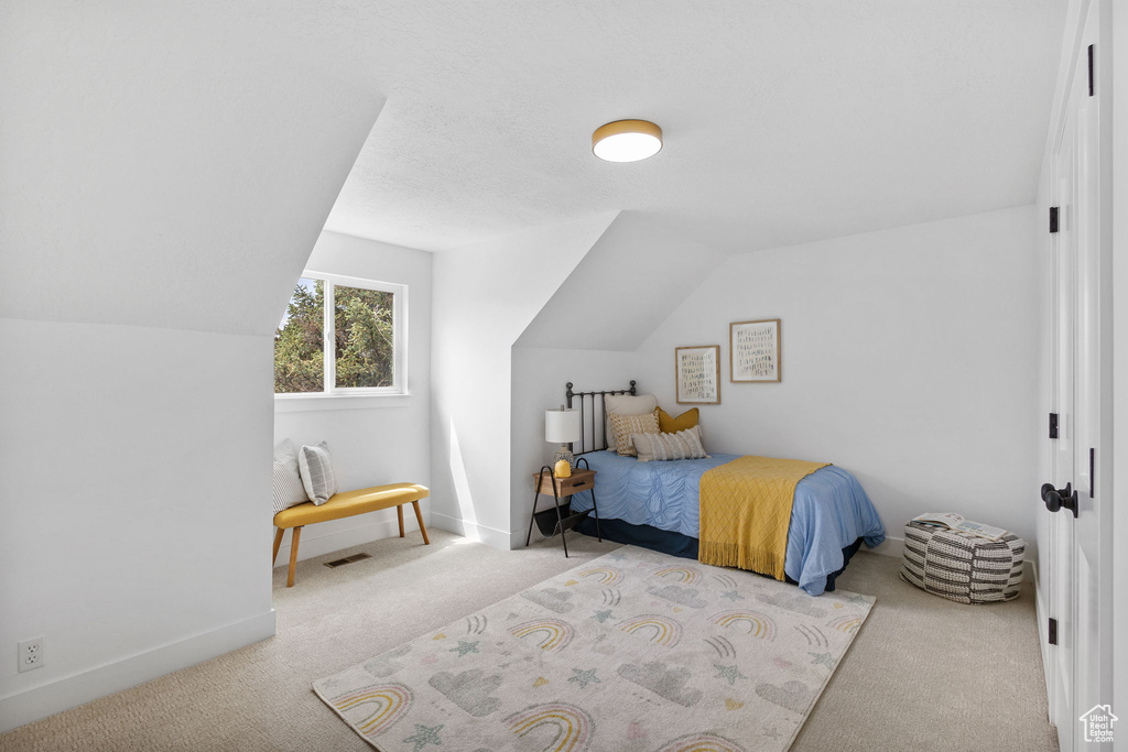 Bedroom with carpet, vaulted ceiling, and baseboards